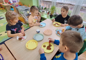 Dzieci ozdabiają ciastka.