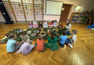 Dzieci siedzą i słuchają panią.