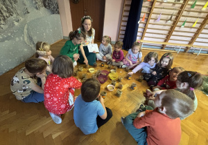 Dzieci siedzą w kole i słuchają instrukcji.