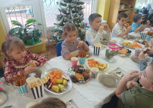 dzieci przy stolikach degustują słodycze, owoce, piją soki