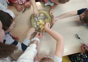 Dzieci mieszają owoce w misce.