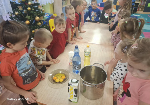 dzieci stoją przy stolikach, na stolikach widać produkty do przygotowania gofrów, jajka, mleko, olej, garnek