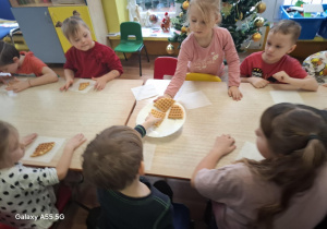 dzieci siedzą przy stolikach, zjadają upieczone gofry