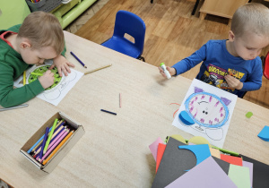 Dzieci wykonują pracę plastyczną przy stolikach.