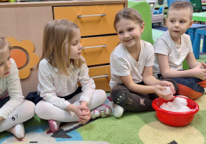 Dzieci siedzą na dywanie i oglądają śnieg.