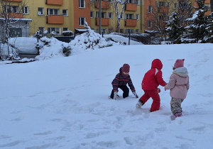 Dzieci bawią się na śniegu w przedszkolnym ogrodzie.