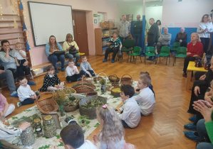 warsztaty ziołowe dla dzieci i ich dziadków, pani o ziół prezentuje sprzęty ogrodnicze, zioła i przyprawy