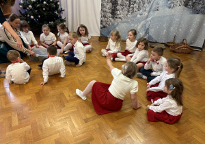 Dzieci siedzą na podłodze.