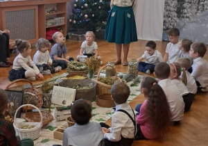 Dzieci siedzą na podłodze wokół rozłożonych ziół.