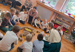 Dzieci siedzą na podłodze wokół rozłożonych ziół.