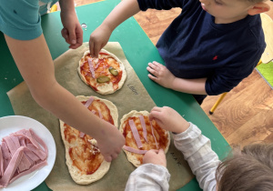 Dzieci komponują swoje pizze.