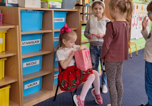 Dzieci podchodzą do dziewczynki siedzącej na krześle.