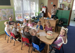 Dzieci siedzą przy stole na którym stoją słodkości.