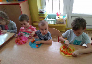 Trzech chłopców kroi warzywa.
