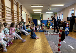 Dzieci siedzą i słuchają funkcjonariuszek miejskich.