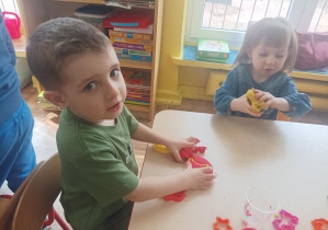 dzieci przy stolikach lepią z ciastoliny, na stolikach leżą kolorowe foremki, pudełka z ciastoliną play doh