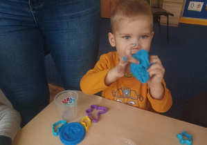dzieci przy stolikach lepią z ciastoliny, na stolikach leżą kolorowe foremki, pudełka z ciastoliną play doh