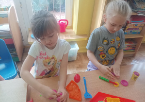 dzieci przy stolikach lepią z ciastoliny, na stolikach leżą kolorowe foremki, pudełka z ciastoliną play doh