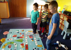 Dzieci grają w podłogową grę planszową.