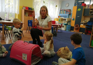 Opiekunka Iwana prezentuje dzieciom z grupy 1 akcesoria dla kota.