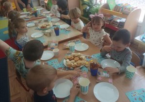 chłopiec świętuje urodziny, dzieci siedzą przy stolikach, na których stoją słodkie przekąski, ciasto, napoje