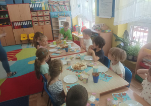 chłopiec świętuje urodziny, dzieci siedzą przy stolikach, na których stoją słodkie przekąski, ciasto, napoje