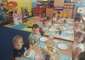 chłopiec świętuje urodziny, dzieci siedzą przy stolikach, na których stoją słodkie przekąski, ciasto, napoje