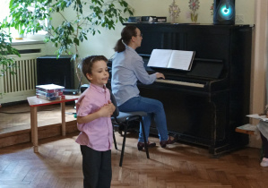 chłopiec śpiewa piosenkę, pani akompaniuje na pianinie