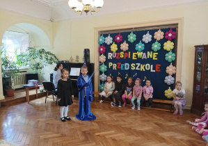 chłopiec i dziewczynka śpiewają piosenkę, pani akompaniuje im na pianinie