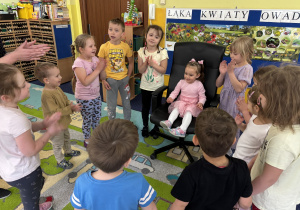 Dzieci ustawione w kole śpiewają "100 lat!".