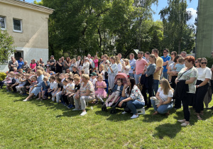 Zgromadzeni gości obserwują program artystyczny przygotowany przez dzieci.