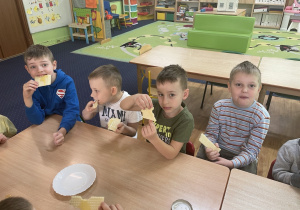 Dzieci siedzą przy stole i zjadają wafle z miodem.