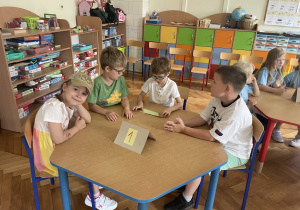 Dzieci siedzą przy stoliku.