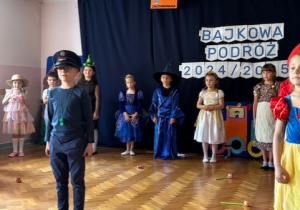 Dzieci ustawione w półkolu, na środku stoi chłopiec przebrany za zawiadowcę stacji.