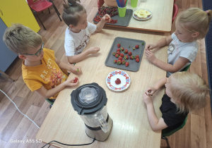 dzieci wykonują owocowy koktajl