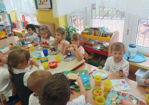 dzieci z grupy drugiej siedzą na ławeczce na sali gimnastycznej