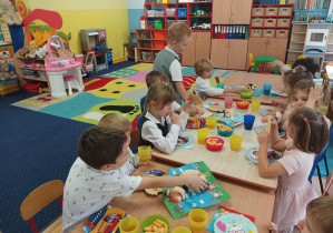 dzieci z grupy drugiej siedzą na ławeczce na sali gimnastycznej