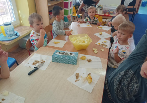 dzieci przy stolikach jedzą potrawy z ziemniaka
