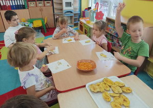 dzieci przy stolikach jedzą potrawy z ziemniaka