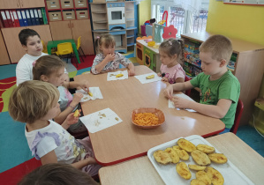 dzieci przy stolikach jedzą potrawy z ziemniaka