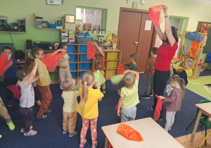 Dzieci bawią się kolorowymi chustkami przy muzyce.