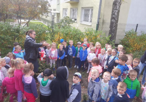Dzieci zgromadzone w kole na dworze słuchają Pani Irminy w jakim celu się tu zebrały.