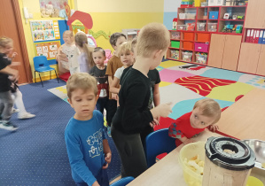 dzieci wrzucają pokrojone owoce do blendera