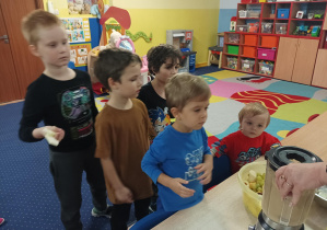 dzieci wrzucają pokrojone owoce do blendera