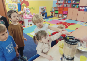dzieci wrzucają pokrojone owoce do blendera