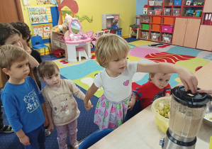 dzieci wrzucają pokrojone owoce do blendera