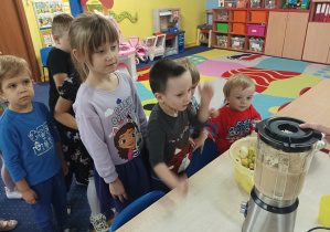 dzieci wrzucają pokrojone owoce do blendera