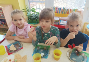 dzieci przy stolikach świętują dzień dziewczynki, na stolikach słodki poczęstunek