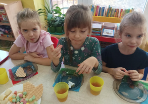 dzieci przy stolikach świętują dzień dziewczynki, na stolikach słodki poczęstunek