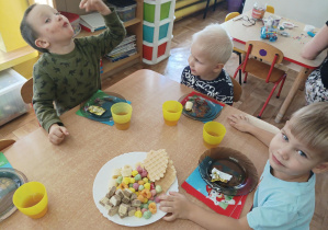 dzieci przy stolikach świętują dzień dziewczynki, na stolikach słodki poczęstunek